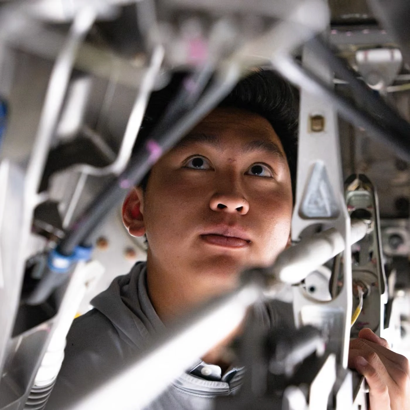 An engineer looking up through the lines and fittings of the hardware overhead